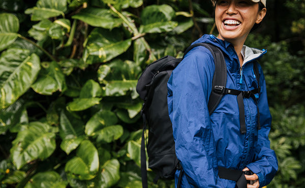 Woman wearing a blue raincoat and smiling while wearing the Shadow Guide 33 on a hike in Hawaii.